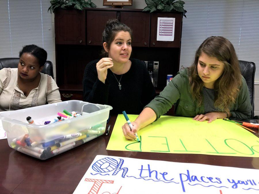 Seniors Bethel Mamo, Melissa Sagaseta, and Karsyn McCluskey design posters to cheer with at the event. 