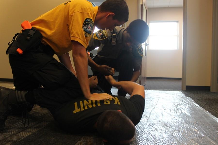Adviser Jason Laroque is pinned to the ground in this overdose scenario. The acting officers are Wagner, who pins Laroque with his knee,  and Bernard who puts the handcuffs on because Laroque simulated becoming aggressive and starting to run away.