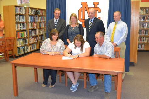 Surrounded by family and administrators, Reid places pen to paper and signs her contract for Shorter University.
