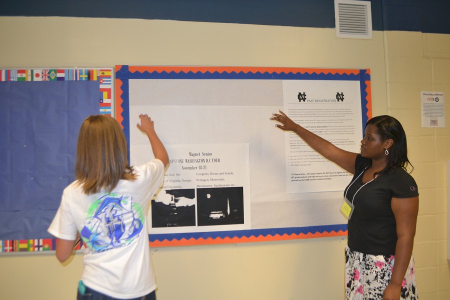 Magnet seniors Mackenzie Union and Dominique Cooper pitch in to reconstruct the Magnet Bulletin Board, a place where SAT information and events will be posted.