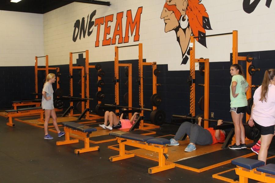 Lacrosse players in the weight training room lifting weights. In addition to this, the girls trained with medicine balls and improved their hand-eye coordination.