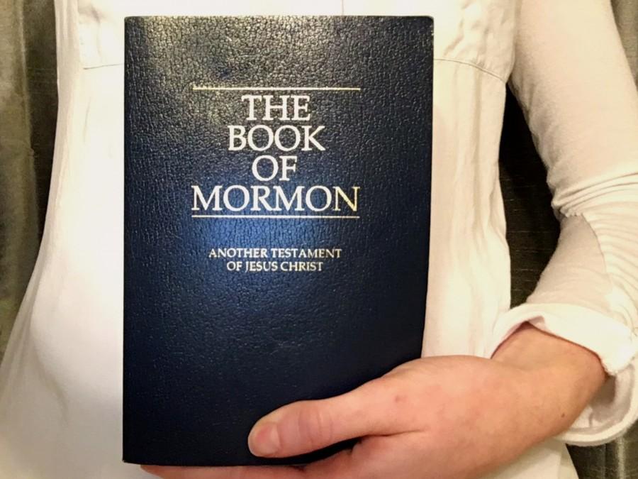 A proud fan displays a Book of Mormon and the standard Mormon dress for proselytizing. 