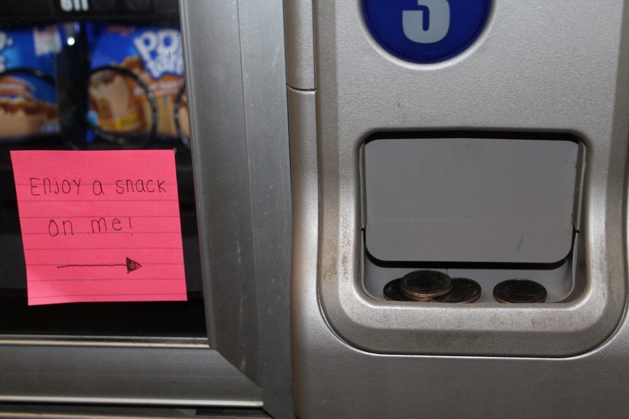 A generous student places her change in a vending machine change slot for the next person to buy a snack without expense. Students approached the machine excitedly, hoping to get a snack on the house.