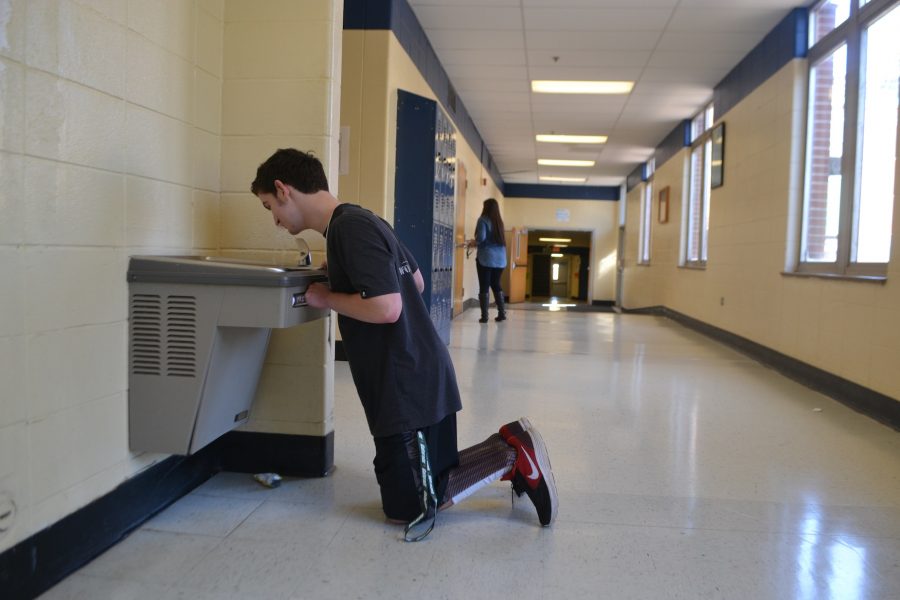 Needing to get on both knees, senior Joshua Joines drinks uncomfortably from the water fountain near the Media Center.
