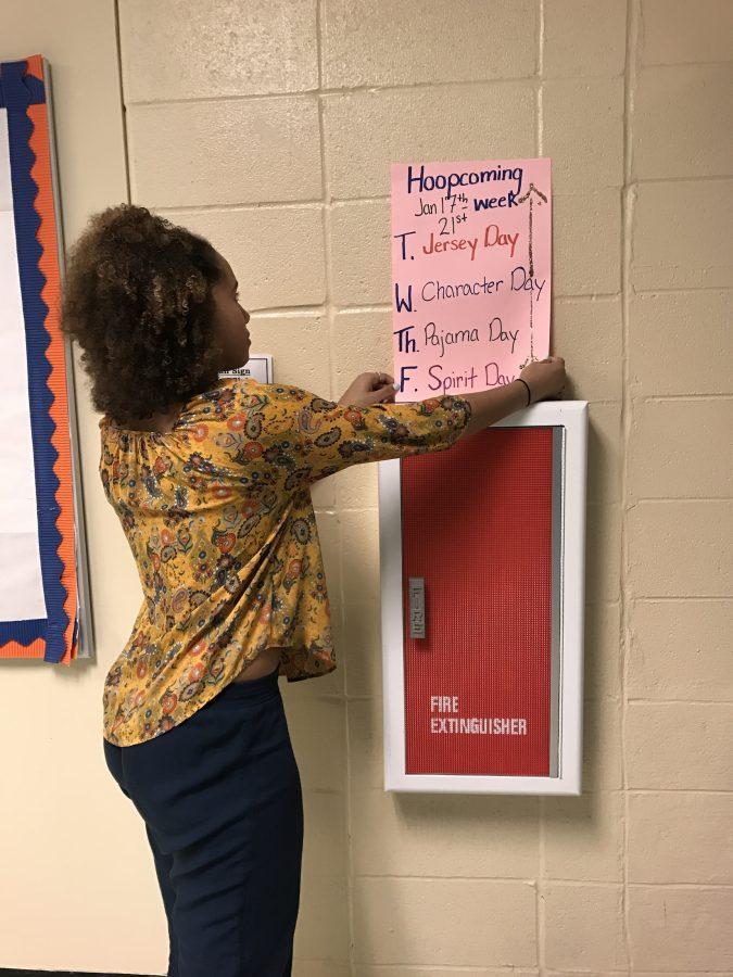 Celina Cotton, a senior at NC and a member of tribal connections, puts up poster advertising the themes for this year’s Hoopcoming week. 
