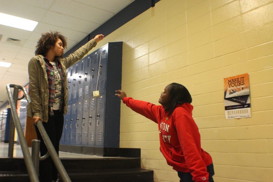 Senior Celina Cotton holds out a dollar while Kesha Perkins reaches out.  Students in the class of 2017 struggle to find ways to pay for their college education, often times seeking scholarships or financial aid. “I don’t want my parents to pay all of my undergraduate education because I know they’ve housed and fed me for the past eighteen years,” Perkins said.