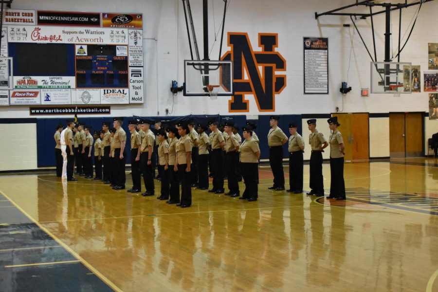 A portion of the NC unit stands at attention as they wait to receive a uniform inspection from the presiding officer. The NC band waits behind them to play during the unit’s ceremony.
