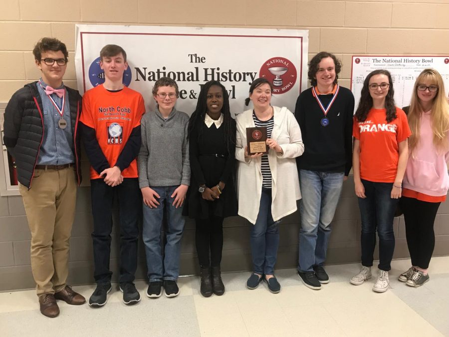 Photo courtesy of Carolyn Glaze. The team of seven joined by NC’s chemistry teacher Ms. Tidrick proudly celebrate their victory in The National History Bee and Bowl. Junior Harrison Glaze and sophomore Chandler Quaile stand proudly displaying their medals and flaunting their triumph. The team awaits the the national tournament in Washington D.C.