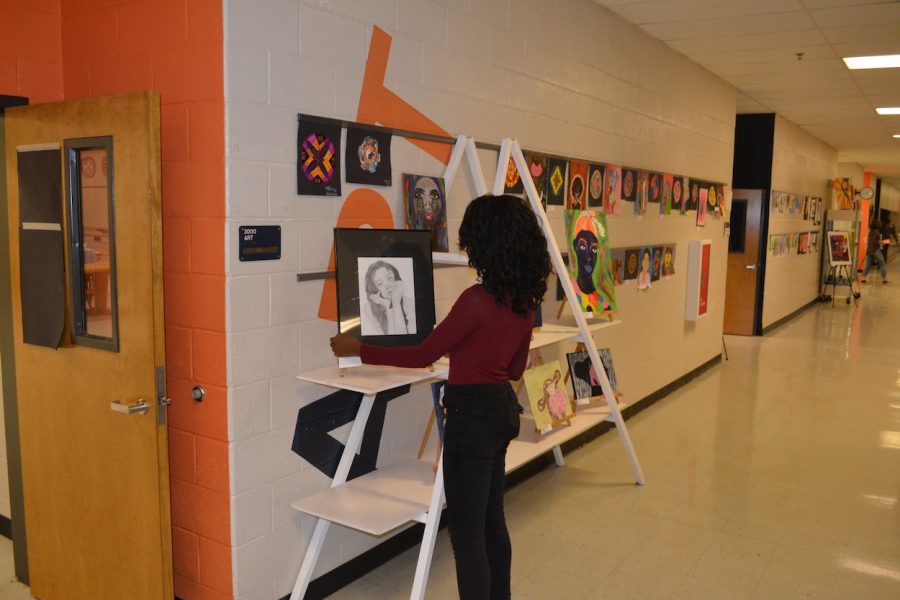 NC art student volunteers to help arrange a display on the day of the annual art show. The show, put on by the art department, allows students to display their hard work while raising funds for the program. “The annual fall art show is an exciting time for our school community. The art show is our biggest fundraiser for the visual arts department and everything for sale or donation is handmade by students,” NC art teacher Dorothy Reavis said.