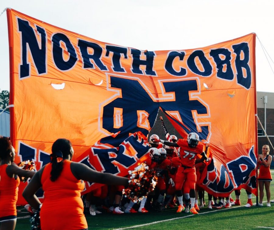 NC’s Varsity Football team broke through the flag at the start of the scrimmage, igniting screams and cheers from the crowd of students, parents, and alumni. The team played hard against the Harrison Hoyas on Friday, August 10.