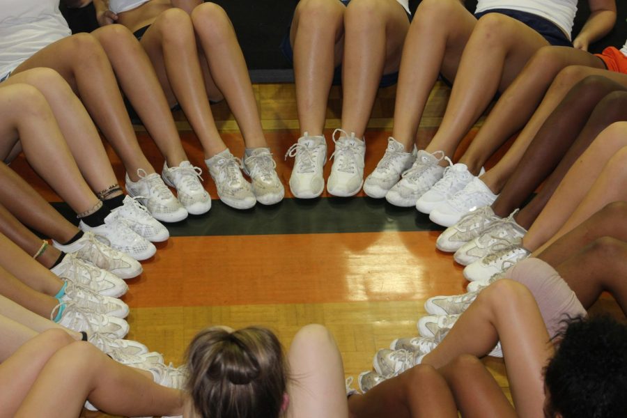 The+cheer+girls+huddle+up+and+build+the+team+spirit+in+their+cheer+circle.+After+hours+of+practice+in+a+warm+gym%2C+the+exhausted+cheerleaders+still+keep+the+spirit+alive+by+creating+this+spirit+driven+circle.+%E2%80%9COn+three+girls%2C+One...two...three...We+are+orange%21%E2%80%9D+the+cheerleaders+chant+as+they+get+back+up+to+continue+tumbling+into+competition.+