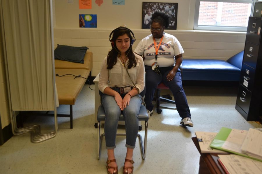Sophomore Julyana Ayache sits with the nurse for her annual hearing and vision test. If the student does not pass the screening, they must visit  a hearing or vision specialist to make sure their eyes and ears function correctly. 