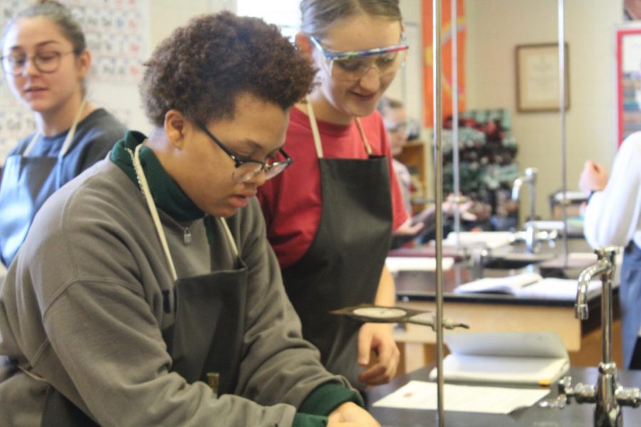 Sophomores Jenna Saaskilati and Jaden Coleman, take on the challenge of their first Honors Chemistry lab by plating pennies, turning them from a copper brown to a bright silver and gold. By carefully following specific procedures they learn about chemical reactions and changes. “We are learning about chemical changes in this lab,” Coleman said. 