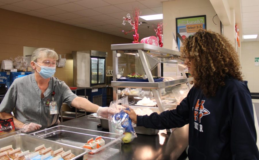 NC cafeteria staff member of 25 years, Martha Cothran, serves sophomore Ryan Lacey school lunch. “When I look at staff members, its often difficult to read or even see their name tags. I think that students would be able to build better relationships with the staff in our school if they could at least more easily learn their names,” Lacey said. Workers come in before school to serve breakfast, then begin cooking and preparing lunches before A lunch, starting at 11:51, until D lunch ending at 1:57. After all lunch periods end, they clean the kitchen and wash used dishes and equipment. 