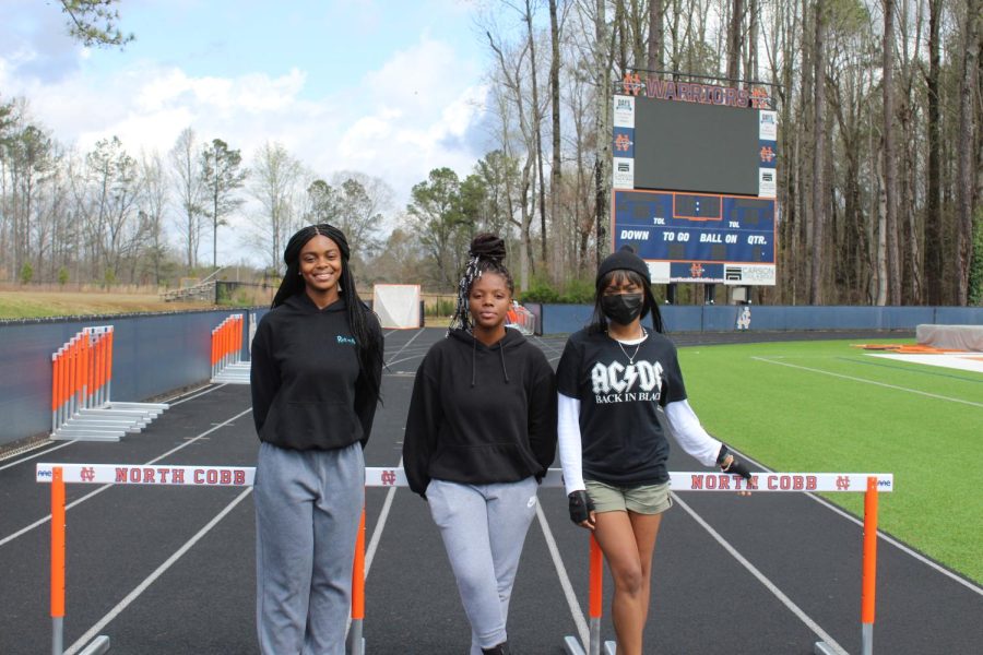 Track and field athletes Zakiya Schloss (left), Sydney Fulford (middle), and Nadia Estime (right) pose on the hurdles in anticipation for tonight’s meet. Tonight North Cobb Highschool hosts the first home track meet in almost 8 years. Field events start at 5 and running events start at 6. North Cobb, North Cobb Christian, Cumberland Christian Academy, and Campbell high school compete against each other tonight. “Im very excited for tonight. Now that our facilities are up to date, we can  finally host a meet. I hope North Cobb can host more track meets in the future now that COVID has lessened. I hope tonight everyone shows what they’ve been working on,” track and field coach Chad Tally said.