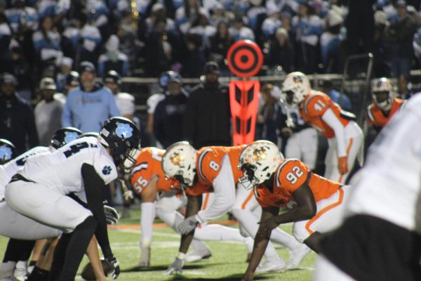 Following an undefeated season and a region title, the NC varsity football team kicks off the first round of Georgia High School Athletics (GHSA) state playoffs against Camden County High School at Emory Sewell Stadium. Ranked as the third-best offense in the state, Camden posed as a difficult opponent to defeat. While slow to start, NC held Camden to seven points and scored 28 to advance to the second round of playoffs. NC defense rapidly shuts down a Camden offensive play.